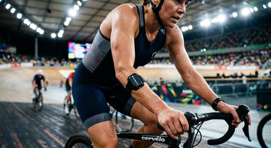 A close-up of a triathlete's arm showing the FLOWBIO S1 sensor during a high-intensity cycling session in bright stadium lighting.