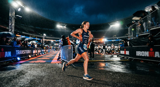 A professional triathlete in a high-speed motion blur, racing through a moody urban transition zone under dramatic, cinematic stadium lighting.
