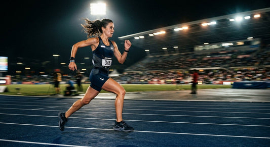 Endurance runner sprinting on a track under cinematic stadium lighting showing motion blur