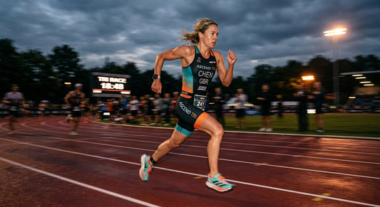 High-speed action shot of a professional triathlete running on a track at dusk with motion blur and sharp focus.