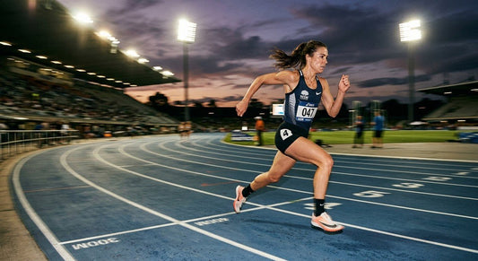 A professional endurance runner sprinting on a track at dusk with dramatic cinematic stadium lighting and motion blur