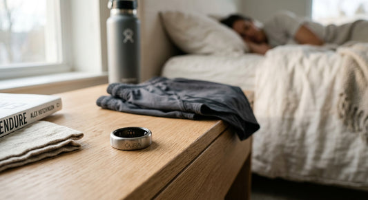 A sleek Oura Ring Gen 4 resting on a minimalist wooden bedside table with soft morning light, highlighting its titanium finish and subtle profile.