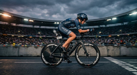 A professional triathlete in a full aero tuck on a carbon time-trial bike, captured with high-speed motion blur against a dramatic, moody stadium background.