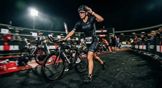 A triathlete performing a high-speed transition from a bike to a run in a moody stadium setting with cinematic lighting and motion blur