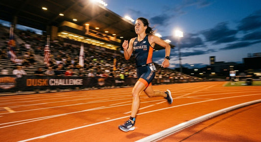 A triathlete running on a track at dusk, captured with high-speed motion blur and dramatic stadium lighting to emphasise intensity.
