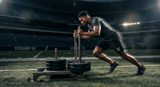A professional athlete performing a high-intensity sled push in a cinematic stadium with moody, dramatic lighting and realistic motion blur.