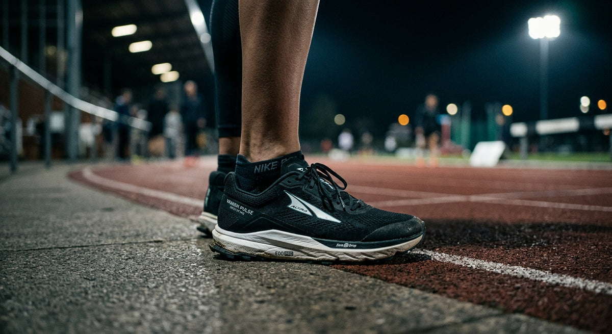 A close-up, moody shot of the Altra Vanish Pulse prototype with a blurred track background and cinematic stadium lighting.