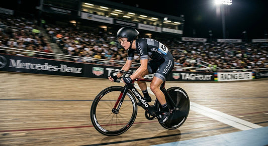 A professional cyclist in a high-speed motion blur, captured with sharp focus and dramatic stadium lighting.