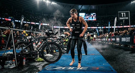A professional triathlete in a high-speed transition, quickly removing a wetsuit in a moody, cinematic stadium setting with dramatic lighting.