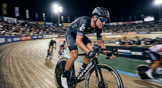 A professional cyclist wearing Bollé C-Shifter sunglasses during a high-speed sprint in a stadium, featuring motion blur and dramatic cinematic lighting.
