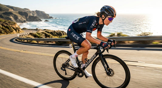 Professional cyclist wearing high-performance wrap-around sunglasses during a high-speed sprint on a sun-drenched road.