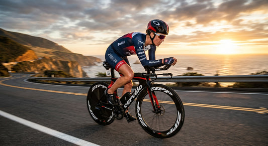 A professional triathlete in a sleek sleeved trisuit cycling at high speed on a coastal road during a golden hour sunset, capturing motion blur and intense focus.