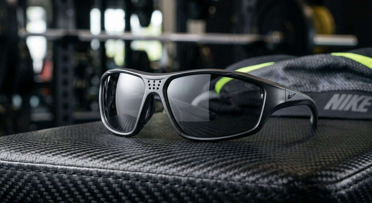 A close-up shot of the Nike Vision Cool Down sunglasses resting on a carbon-fibre surface, highlighting the sleek, aerodynamic frame geometry and ventilated bridge.