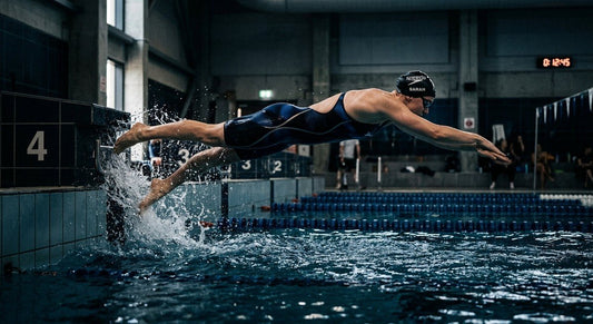 High-speed photography of a swimmer pushing off the wall in a cinematic, moody indoor pool environment.