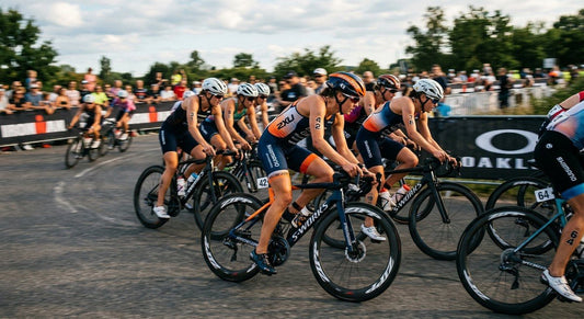 A professional triathlete in a tight pack of cyclists during a draft-legal race, captured with high-speed motion blur.