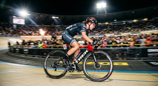 A professional cyclist in high-speed motion blur, illuminated by dramatic stadium lighting with sharp textures on the bike frame.