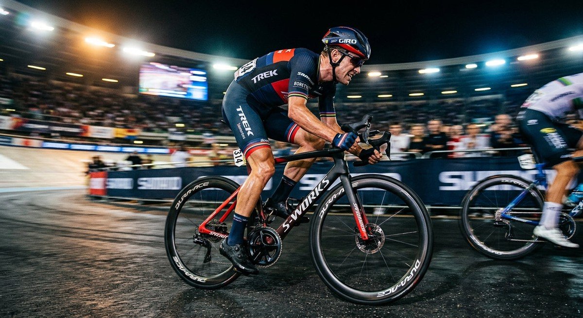 Professional cyclist sprinting on a high-end carbon road bike with motion blur and dramatic stadium lighting