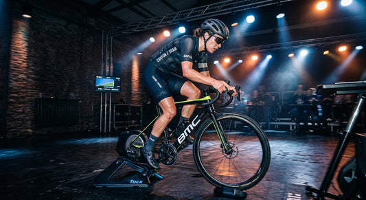 Professional cyclist training on a smart trainer in a dark, atmospheric room with dramatic stadium lighting and high-speed motion blur.