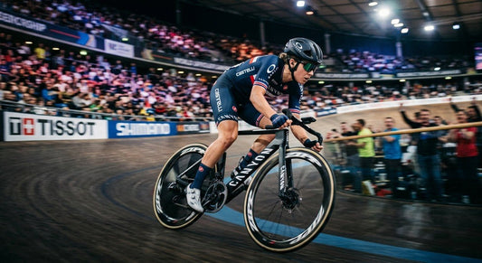 High-speed action shot of a professional cyclist wearing Oakley Sutro Lite Sweep glasses in a stadium with motion blur.