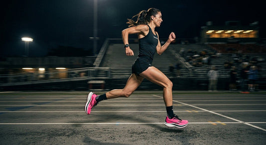 A sleek, professional side-profile shot of the Saucony Endorphin Elite 3 in a dark, moody stadium environment with dramatic motion blur.