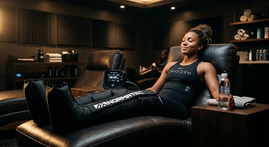 A professional athlete wearing sleek, modern pneumatic compression boots while resting in a dimly lit, cinematic sports recovery lounge.