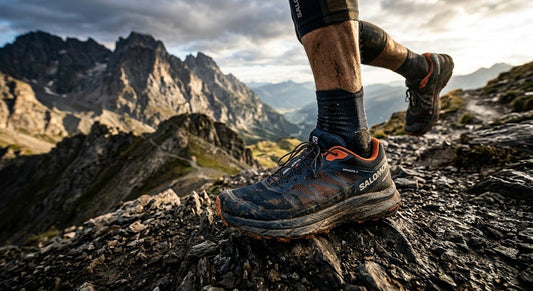 A close-up of the Salomon Genesis 2 trail running shoe in a rugged mountain environment with dramatic lighting and high-contrast textures.