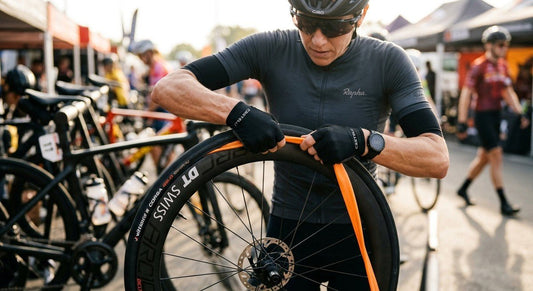 A close-up of a high-performance road bike wheel featuring a lightweight TPU inner tube being installed by a cyclist.