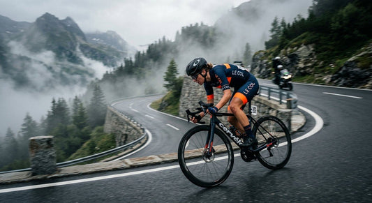 A professional cyclist in a tight tuck descending a misty alpine mountain pass at high speed with motion blur.