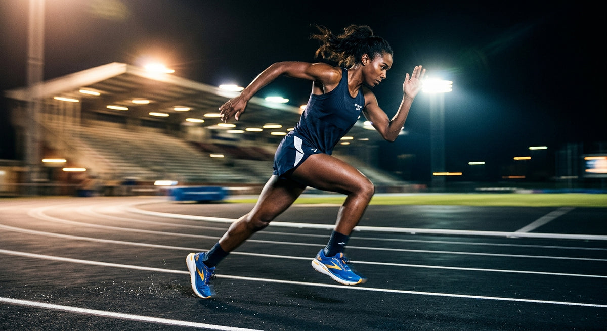 High-speed action shot of a runner wearing Brooks Ghost Max 4 shoes on a track with dramatic stadium lighting and motion blur.
