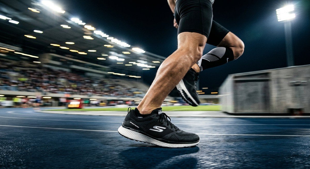 A sleek, professional side-profile shot of the Skechers Aero Burst featuring a dynamic motion blur background with sharp stadium lighting.