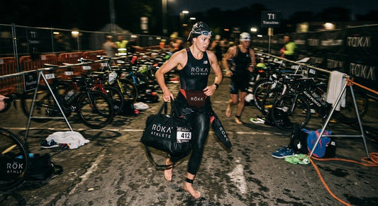 A professional triathlete standing in a dimly lit transition zone with a ROKA bag, captured in high-speed motion blur.