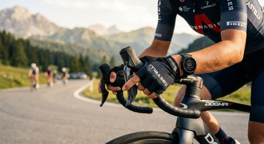A close-up shot of a professional cyclist's hand shifting a wireless electronic derailleur with a blurry background of a sun-drenched mountain road.