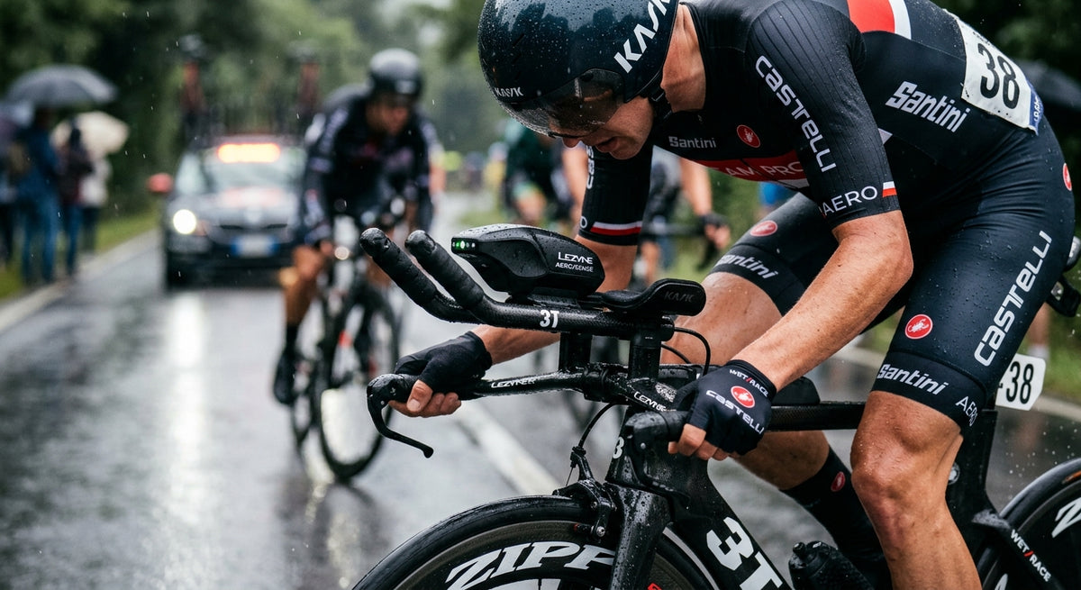 A close-up of a high-tech aerodynamic sensor mounted between carbon fibre aero bars on a time trial bike during a rainy race.