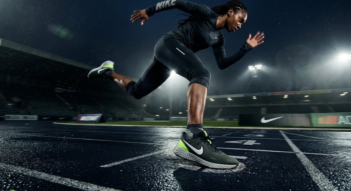 High-speed action shot of the Nike Revolution 9 running shoe on a dramatic stadium track with moody cinematic lighting