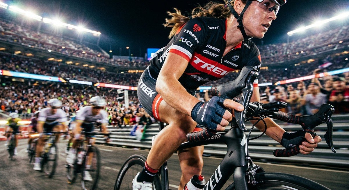 Close-up of a professional cyclist shifting gears on a carbon road bike with cinematic stadium lighting and motion blur