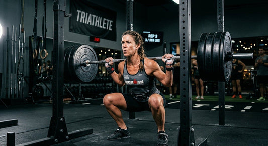 A master triathlete performing a heavy barbell back squat in a high-tech gym with dramatic cinematic lighting and sharp focus.