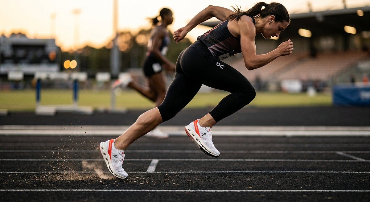 A side-profile shot of the On Running Cloudboom Strike 2 on a track, captured with high-speed photography to emphasise the sleek, aerodynamic silhouette and crisp texture of the engineered mesh.