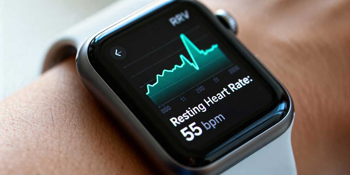 A close-up photograph of a smartwatch screen displaying heart rate variability data, highlighting the importance of tracking physiological metrics over physical appearance.