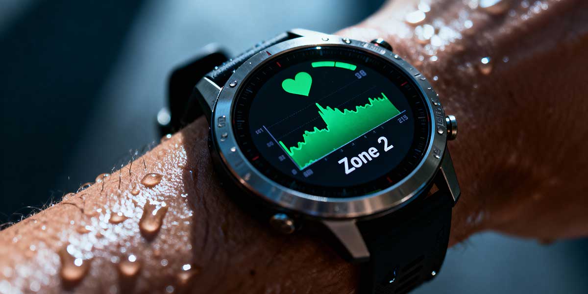 Close-up macro shot of a smart sports watch displaying real-time heart rate zone data on a sweating athlete's wrist, illustrating data-driven training.