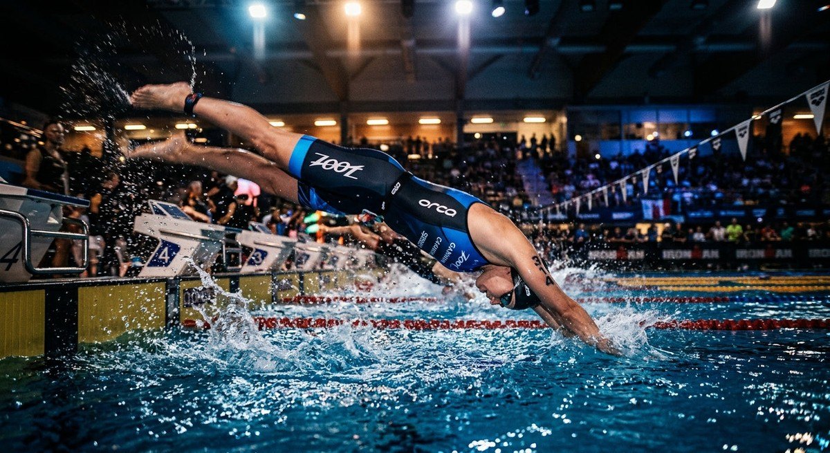 A blurry, high-motion action shot of a triathlete diving into a swimming pool with cinematic lighting effects.