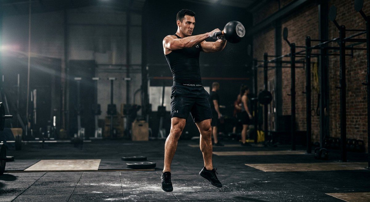 A cinematic shot of a kettlebell swing in motion, capturing the intense focus and muscular detail of a fitness enthusiast in mid-air.