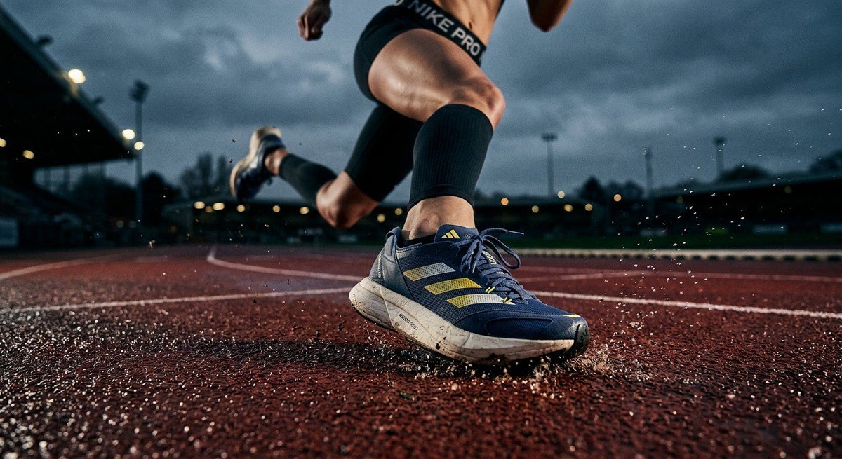 A close-up action shot of a runner's feet hitting the track in high-speed, featuring dramatic contrast, sharp details of athletic trainers, and a moody, professional atmosphere.