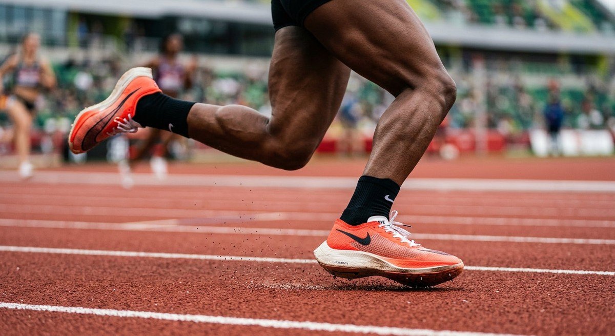 A close-up, high-speed action shot of an athlete's feet hitting the track, showing fine details of the running shoes and realistic muscle tension.
