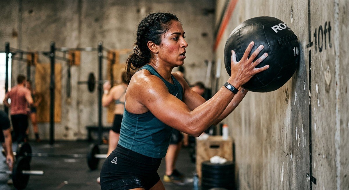 A close-up shot of a competitive fitness athlete performing a wall ball exercise with intense focus and realistic texture details.
