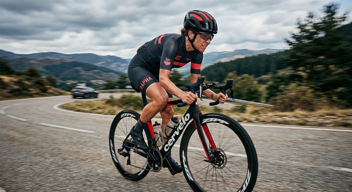 A cyclist intensely focused on the road ahead during a long endurance training session, with sharp focus on the rider and a cinematic motion-blurred background.