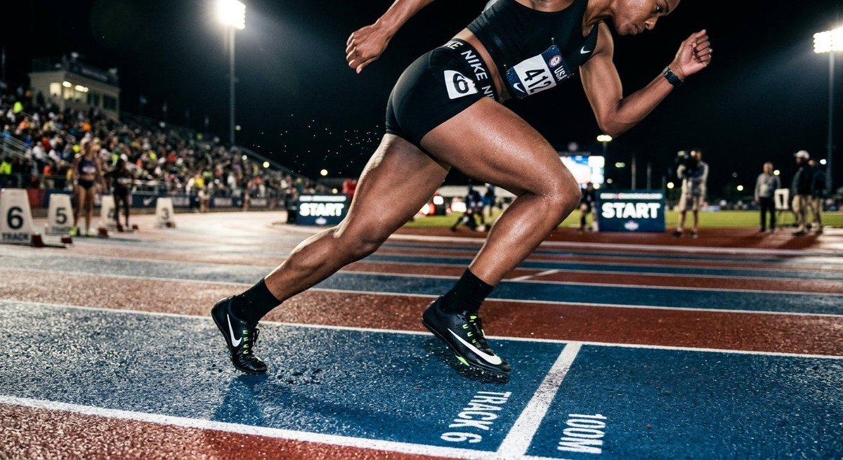 A high-speed cinematic image of an athlete's leg impacting the track with visible motion blur and realistic sweat droplets, captured under moody, high-contrast stadium lighting.