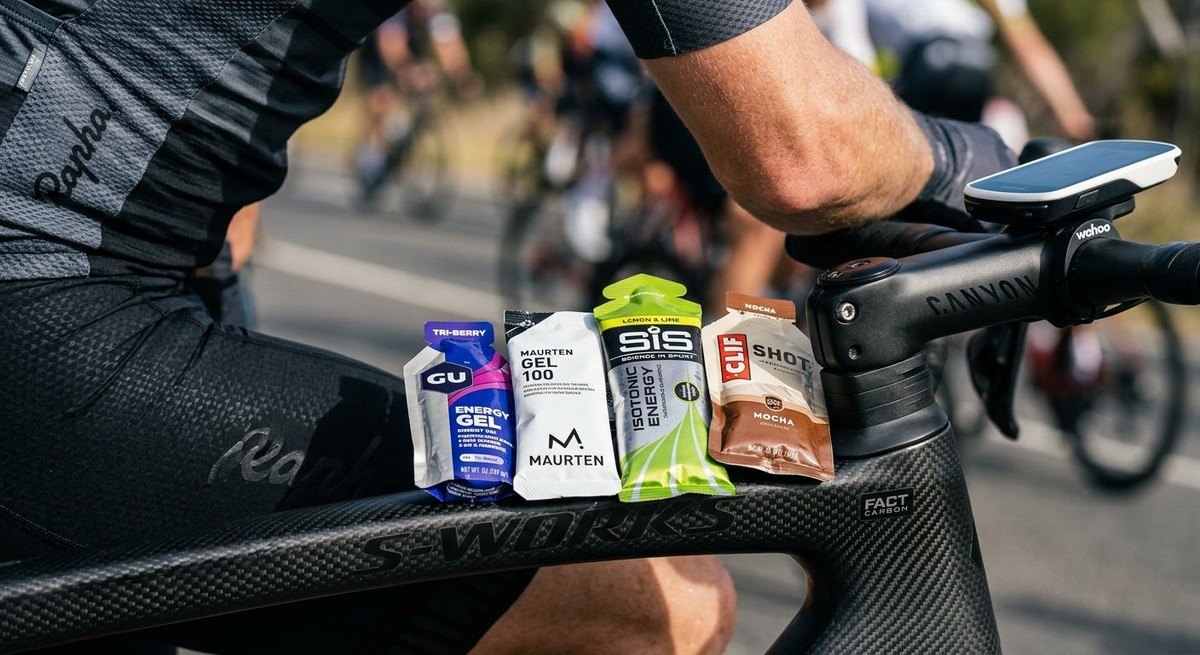 A macro shot of performance nutrition gels arranged on a carbon fibre cycling component, highlighting the precision of modern endurance sports equipment.