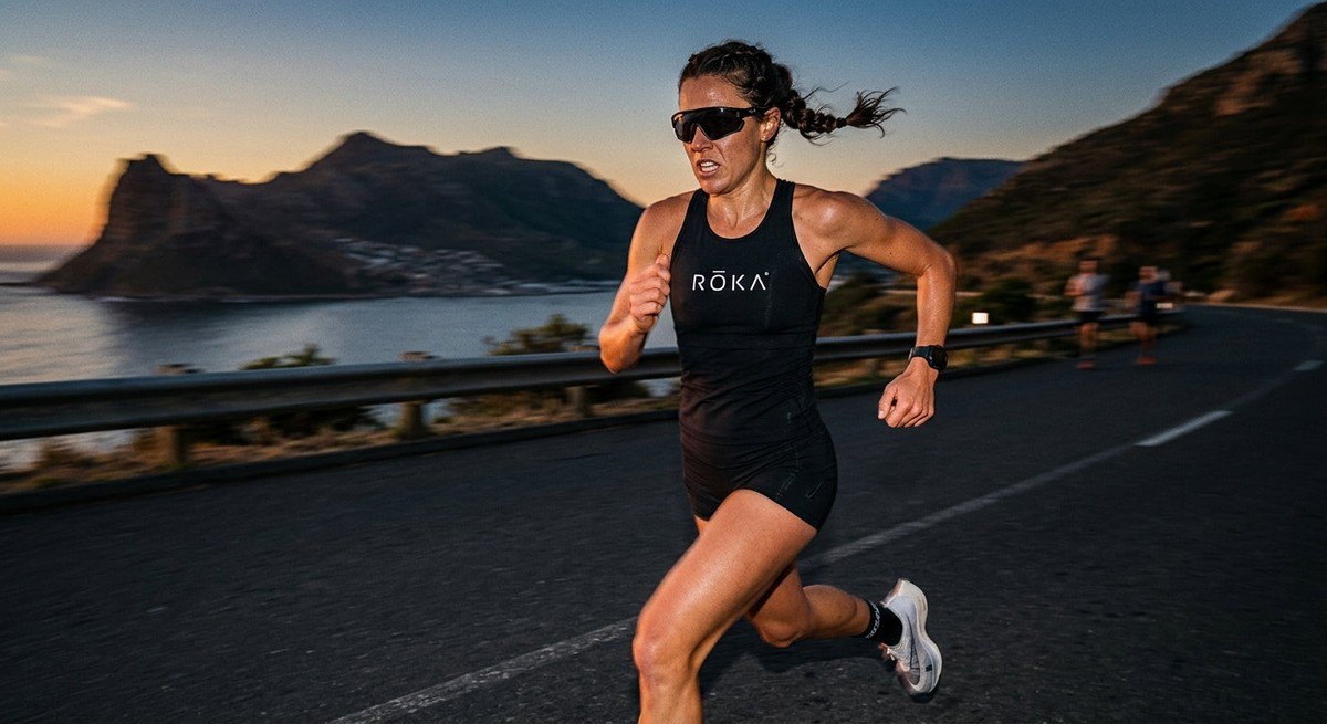 A professional athlete running in a blur of motion, wearing the sleek, aerodynamic ROKA Cade 2.0 sunglasses with cinematic contrast.