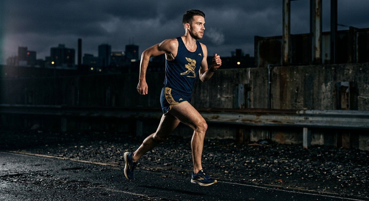 A professional athletic portrait featuring the Tracksmith Eliot Ryder against a dark, moody background with sharp textural focus.