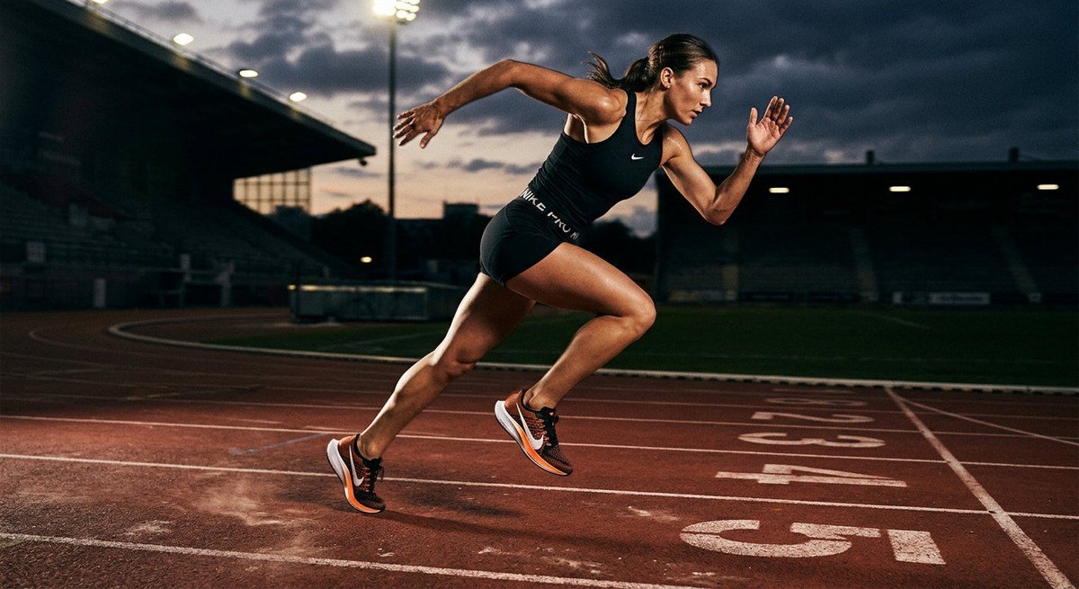 A runner wearing the Nike Pegasus Premium 2 sprinting across a track with dramatic shadows and high-contrast lighting to highlight the shoe design.